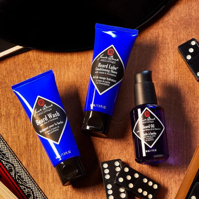 Set of Jack Black beard care products on a wooden surface with dominoes.