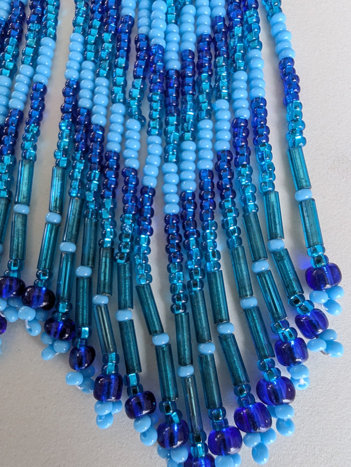 Close-up of blue and green beaded earrings on a light background
