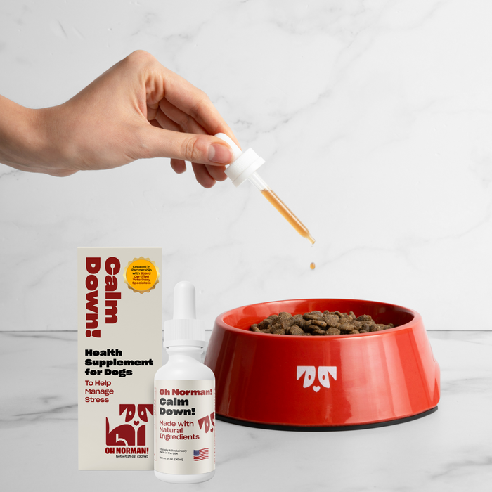 Front view of Calm Down! calming supplement bottle and box with dropper releasing liquid into red bowl on marble background