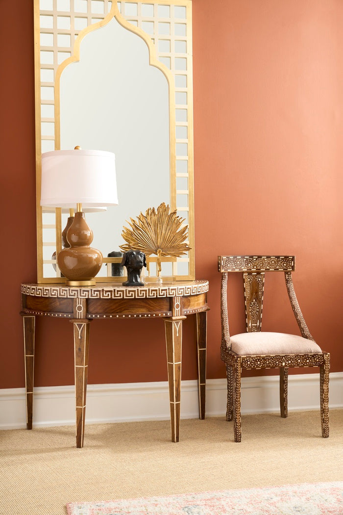 Decorative table with lamp and chair against a brown wall