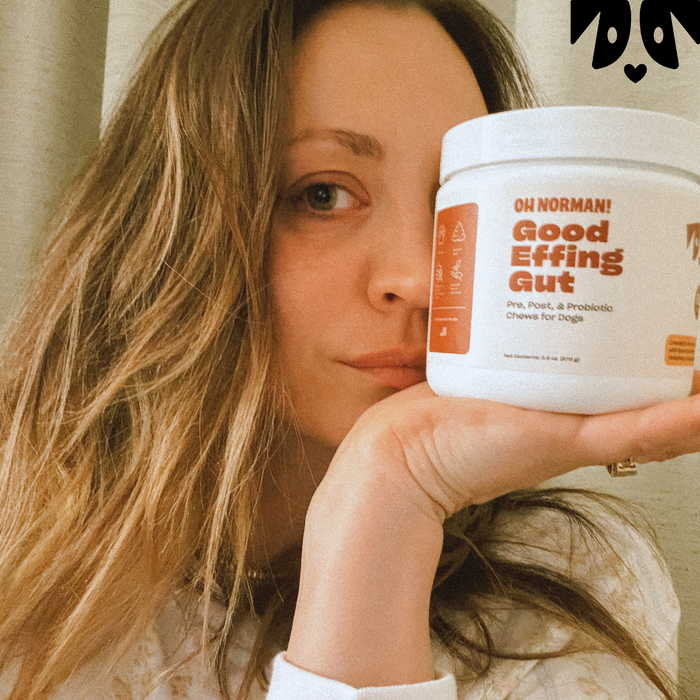 Kaley Cuoco holding a container labeled 'OH NORMAN! Good Effing Gut Pre, Post, & Probiotic Chews for Dogs'