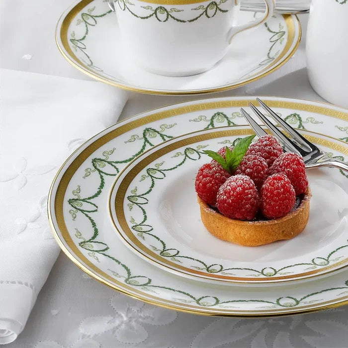 Decorative plate with a tartlet and raspberries on a matching plate with gold and green rim.