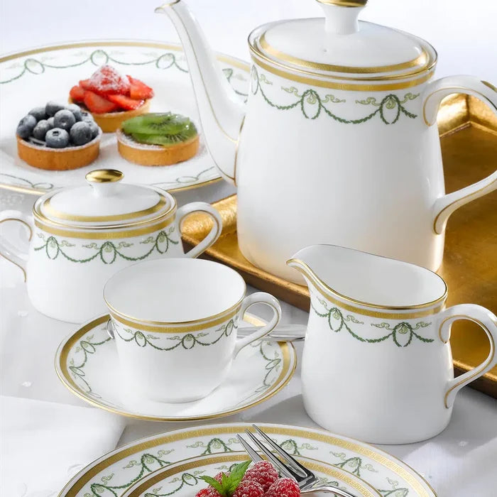 Tea set with teapot, cups, and saucers on a tray with pastries.